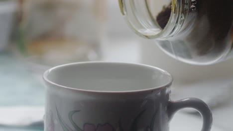 Slow-motion-close-up-of-a-hand-holding-a-glass-of-coffee-spilling-into-a-mug