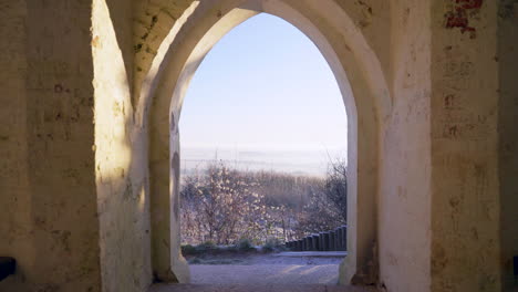Wide-shot-of-monument-archway-looking-out-at-winter-heavy-frost-fields-4K