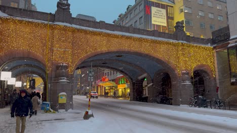 Christmas-lights-adorn-snowy-Kungsgatan,-Stockholm,-with-bustling-evening-life