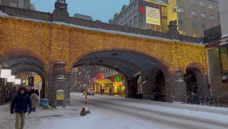 Las-Luces-Navideñas-Adornan-El-Nevado-Kungsgatan,-Estocolmo,-Con-Una-Animada-Vida-Nocturna