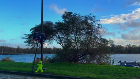 Wind-from-storm-blows-powerfully-through-tree-on-bank-of-water