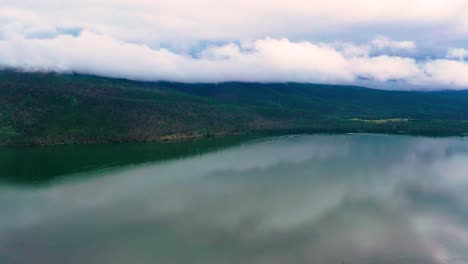 Hermoso-Lago-Claro-Con-Impresionantes-Colinas-Nubladas-En-El-Fondo-De-Un-Tranquilo-Embalse-De-Montaña