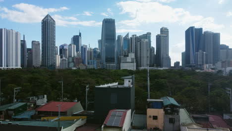 Aerial-view-rising-over-homes,-approaching-the-Metro-Manila-skyline-in-Philippines