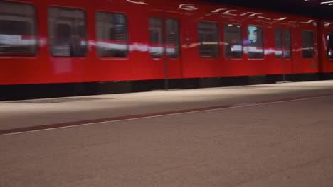 Woman-walks-along-subway-station-platform-as-train-departs,-Helsinki
