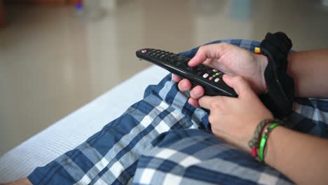 Hand-Einer-Person-Mit-Der-Fernbedienung-Des-Fernsehers-Auf-Dem-Sofa-Zu-Hause