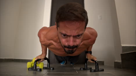 Slow-motion-close-up-of-a-latin-hispanic-fit-man-training-at-home-doing-push-ups-using-support-bars