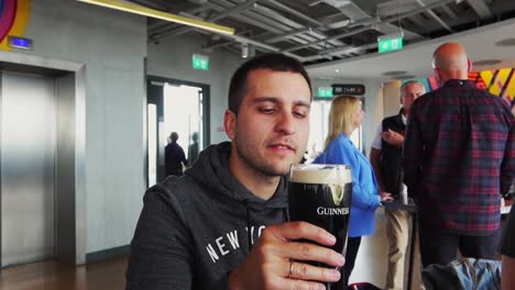 Young-man-holds-a-glass-of-dark,-freshly-poured,-frothy-Guinness-beer