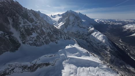 Smooth-aerial-shot-over-the-snowy-french-alps-on-a-sunny-day-with-clear-blue-sky-in-Chamonix-region