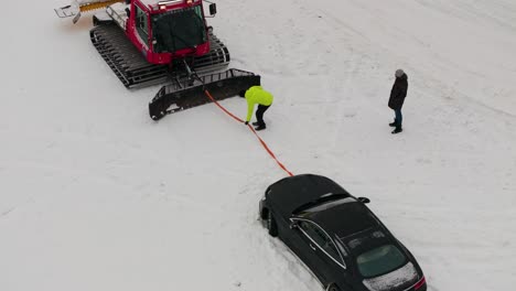Persona-Sujeta-La-Cuerda-Entre-El-Snowcat-Y-El-Coche-Durante-El-Proceso-De-Evacuación,-Austria