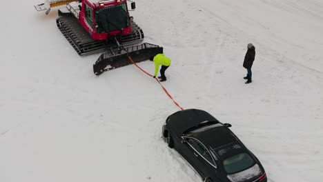 Person-Hält-Seil-Zwischen-Pistenraupe-Und-Auto-Während-Der-Evakuierung,-Österreich