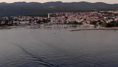 Beautiful-coastline-of-Novi-Vinodolski,-Croatia,-Marina-Novi,-Old-town,-harbour,-seaside-town,-Adriatic-Sea,-speedboat-leaving-the-port,-pier,-dock,-jetty,-sailboat,-sunset,-mediterranean-landscape