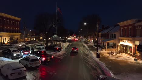 Abendlicher-Blick-Auf-Eine-Verschneite-Hauptstraße-Mit-Geparkten-Autos-Und-Beleuchteten-Gebäuden