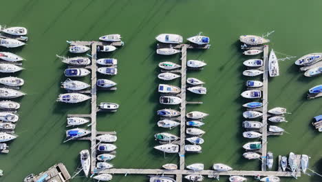 Wide-aerial-shot-flying-over-Hamble-River-boatyard-with-many-yachts-and-boats-moored-onto-jetties