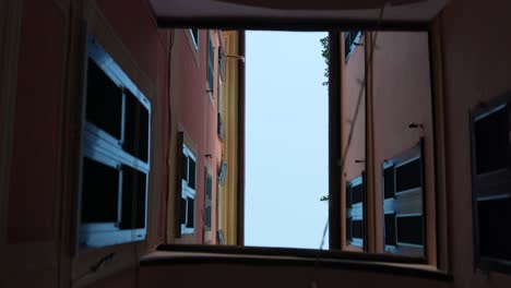 Looking-up-while-walking-between-colorful-neighborhood-buildings,-Varazze,-Italy