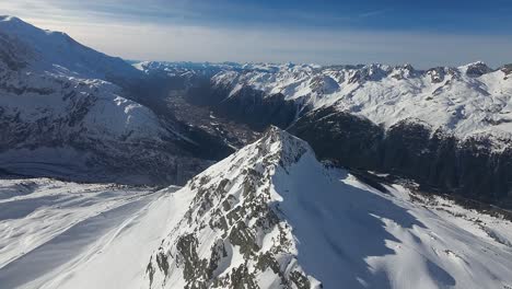 Eine-Ausgedehnte-Luftaufnahme-Einer-Atemberaubenden-Alpenlandschaft-Mit-Einem-Scharfen-Bergrücken,-Der-Zu-Schneebedeckten-Gipfeln-Unter-Einem-Klaren-Himmel-Führt