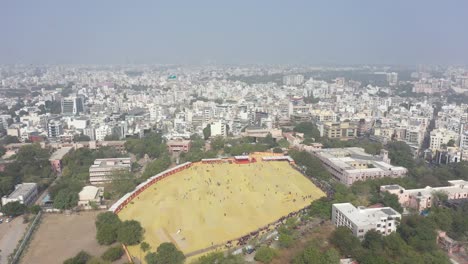 Rajkot-kite-festival-aerial-drone-shot-There-is-a-large-field-surrounded-by-bushes-where-many-tourists-are-flying-different-kites-from-the-field