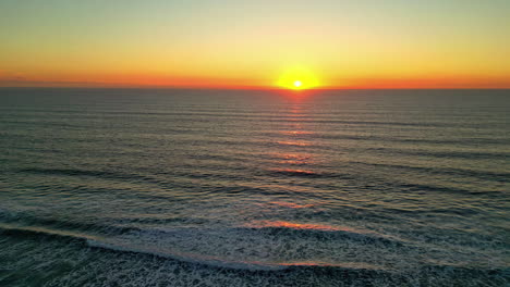 Wunderschöner-Gelb-Leuchtender-Sonnenuntergang-Am-Horizont-Mit-Meereswellen,-Die-über-Den-Strand-Rollen