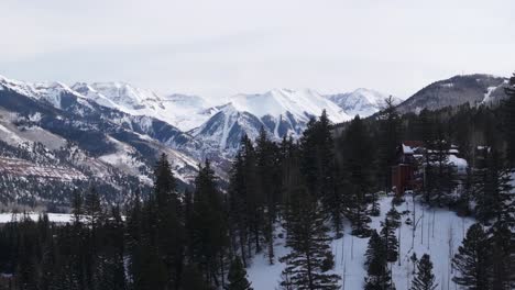 Paisaje-Invernal-De-Montañas-Rocosas-De-Colorado-Sobre-Cabañas-En-La-Colina,-Nieve-Y-Bosque