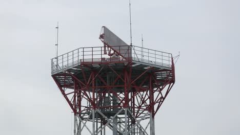 Red-radar-tower-against-overcast-sky,-intricate-metal-structure,-modern-communication