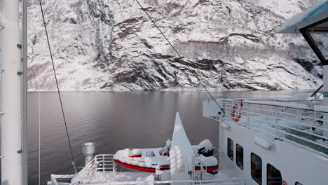 Slow-motion-POV-of-a-winter-ferry-boat-ride-in-Geirangerfjord-to-Geiranger,-Norway,-with-snowy-mountains-and-captivating-fjord-views