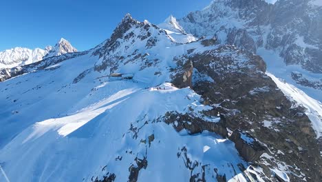 Aerial-view-of-snow-mountain-peaks-in-ski-season-on-a-sunny-day-with-clear-blue-sky