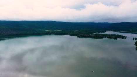 Vista-Aérea-Por-Drones-De-Un-Hermoso-Embalse-De-Montaña-Con-Impresionantes-Colinas-Nubladas-En-El-Fondo-De-Un-Tranquilo-Lago-Claro-Y-Reflejo-De-Nubes-En-El-Agua