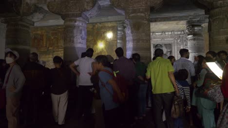 Tourists-watching-painted-mural-artwork-at-the-wall-of-medieval-era-Ajanta-caves