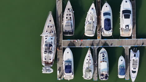 Aerial-shot-birds-eye-view-panning-over-boats-and-yachts-moored-on-jetty-in-boatyard-4K