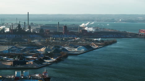 Industrial-harbor-with-smokestacks-and-clear-skies,-daylight,-aerial-view