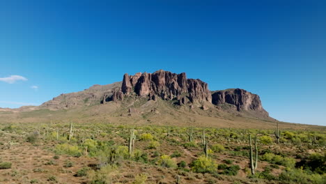 Gradual-establishing-shot-above-saguaro-cactus-and-sandy-desert-southwest-landscape-to-Superstition-Mountains