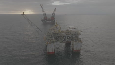 Drohnenaufnahmen-Einer-Offshore-Ölplattform-Und-Eines-Kranschiffs-Bei-Sonnenaufgang-Auf-Dem-Meer