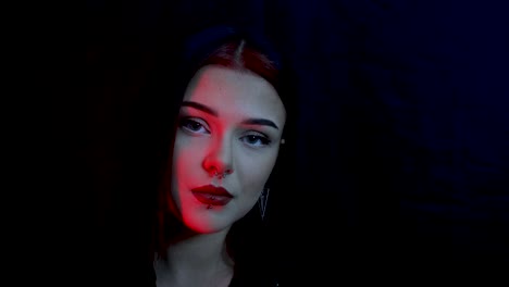 Young-and-stunning-female-model-posing-in-a-dark-red-lit-room-with-a-black-background