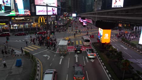Abendlicher-Verkehrsfluss-An-Der-Kreuzung-Bukit-Bintang-Mit-Fußgängern-Und-Neonschildern