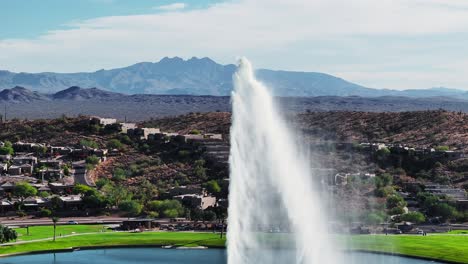 Wasser-Schießt-In-Die-Luft-Und-Wölbt-Sich-Wieder-Nach-Unten,-Mit-Epischer-Aussicht-Auf-Die-Wüste-Im-Südwesten-Der-Berge,-Fountain-Hills,-Arizona,-Luftaufnahme