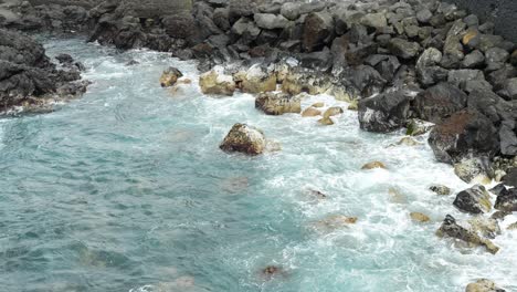 Rocks-being-hit-by-seawater-on-the-seashore-turning-white,-static-closeup-slow-motion-puerto-de-la-cruz-tenerife