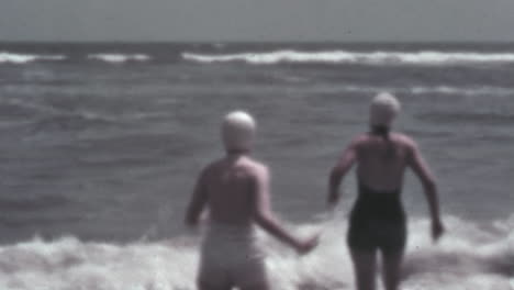 Frauen-In-Klassischen-Badeanzügen-Betreten-Das-Meer-In-Farbigen-Vintage-Aufnahmen-Aus-Den-1930er-Jahren