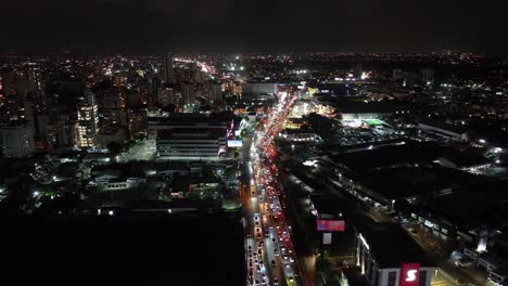 Vista-Aérea-De-Santo-Domingo,-República-Dominicana-Por-La-Noche,-Tráfico-Por-Carretera,-Edificios-Centrales-Y-Luces-De-La-Ciudad