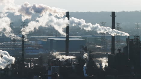 Industrial-landscape-with-smokestacks-emitting-steam-against-a-clear-sky,-distant-view