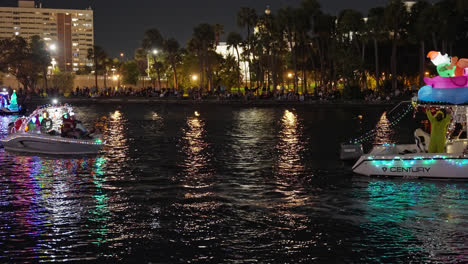 Gente-Celebrando,-Desfile-De-Barcos-Iluminados-Junto-Al-Río-Por-La-Noche-En-Tampa,-Florida