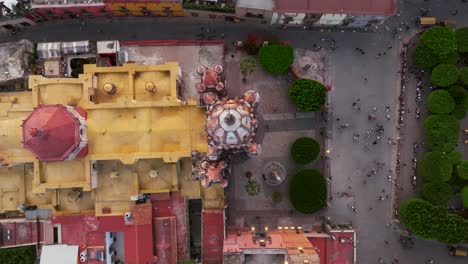 Rising-drone-shot-showing-tourist-on-square-visiting-mexican-cathedral-in-San-Miguel-de-Allende,-Guanajuato