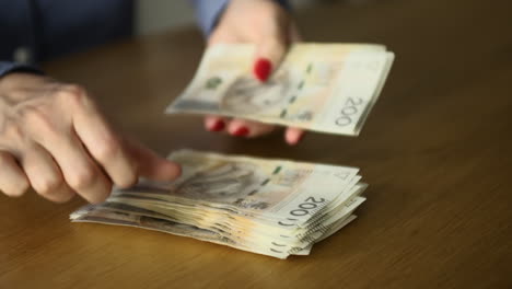 Female-hands-counting-200-Polish-zloty-bills-at-the-table---banking,-business,-and-finance-concept,-close-up-shot