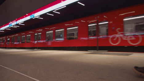 El-Tren-Subterráneo-Rojo-Brillante-Llega-A-La-Estación,-Una-Mujer-Camina-Hacia-El-Tren.