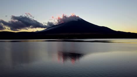 Die-Silhouette-Des-Fuji-In-Der-Abenddämmerung-Mit-Wolken-Spiegelt-Sich-Im-Ruhigen-Wasser-Des-Sees,-Eine-Ruhige-Und-Heitere-Szene