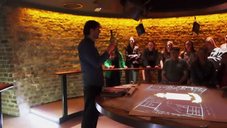 Man-guide-holding-a-wine-bottle-speaking-to-tourists-in-a-whiskey-demonstration