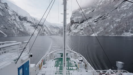 Slow-motion-POV-of-a-winter-ferry-boat-ride-in-Geirangerfjord-to-Geiranger,-Norway,-with-snowy-mountains-and-captivating-fjord-views