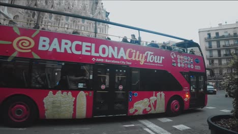 red-double-decker-city-tour-bus-drives-past-the-Sagrada-Familia-Barcelona
