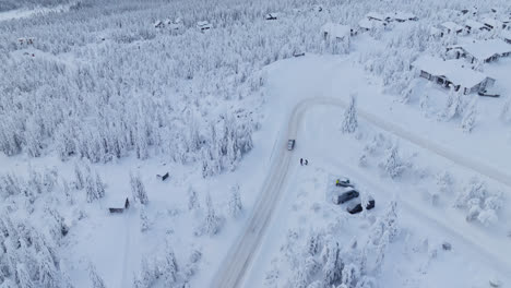 Drone-tracking-a-EV-car-in-middle-of-snowy-forest-and-mountain-cabins-in-Lapland