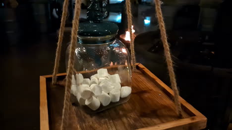 Close-up-panning-view-of-a-jar-with-marshmallows-on-a-wooden-plate