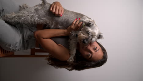 Vertical-slow-motion-of-a-beautiful-brunette-latin-model-carrying-her-schnauzer-dog-and-kissing-it
