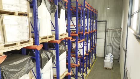 A-warehouse-shelf-laden-with-neatly-stacked-pallets,-heavy-white-bags-placed-on-top